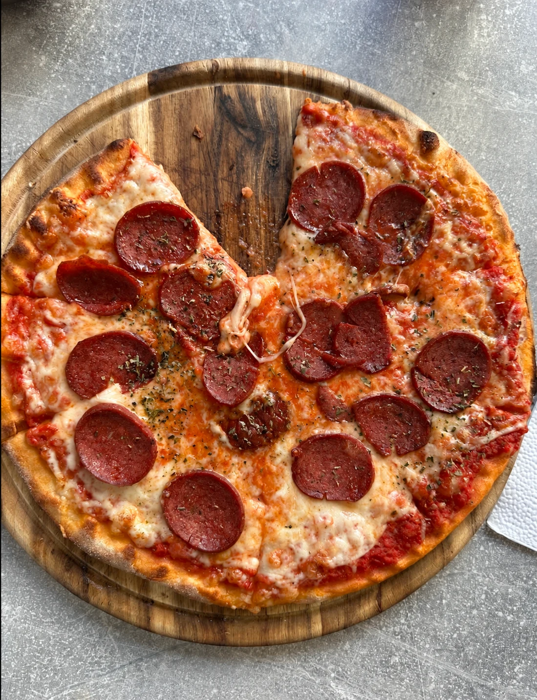 Pizza mit Salami, frisch auf einem Holzbrett serviert